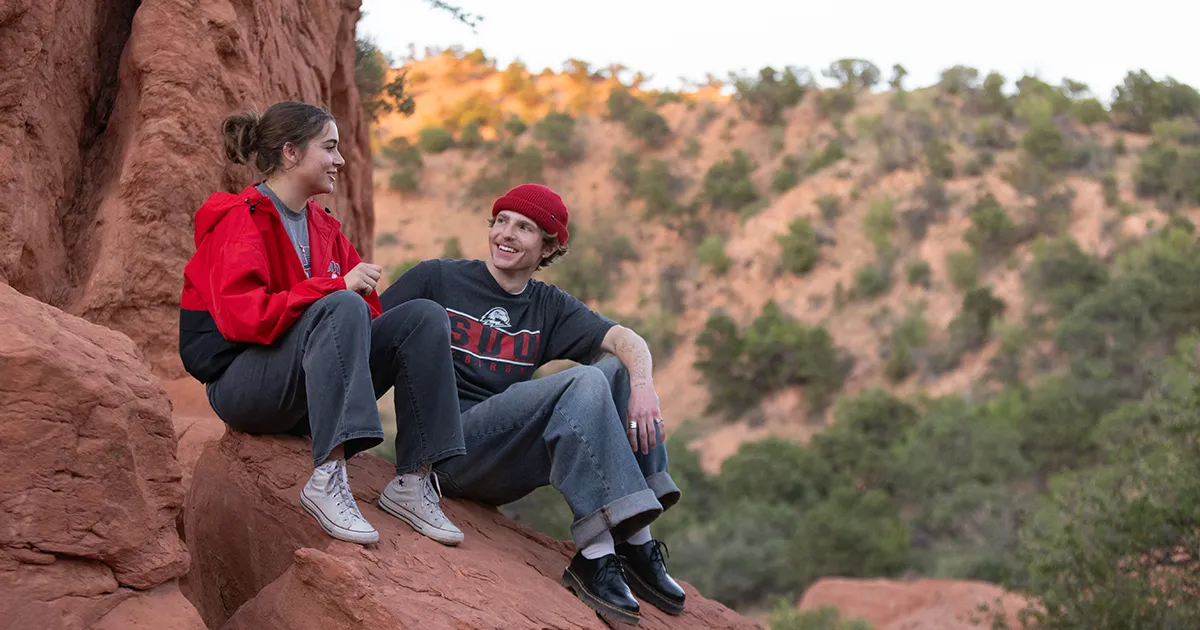 Two students sitting together on a rock