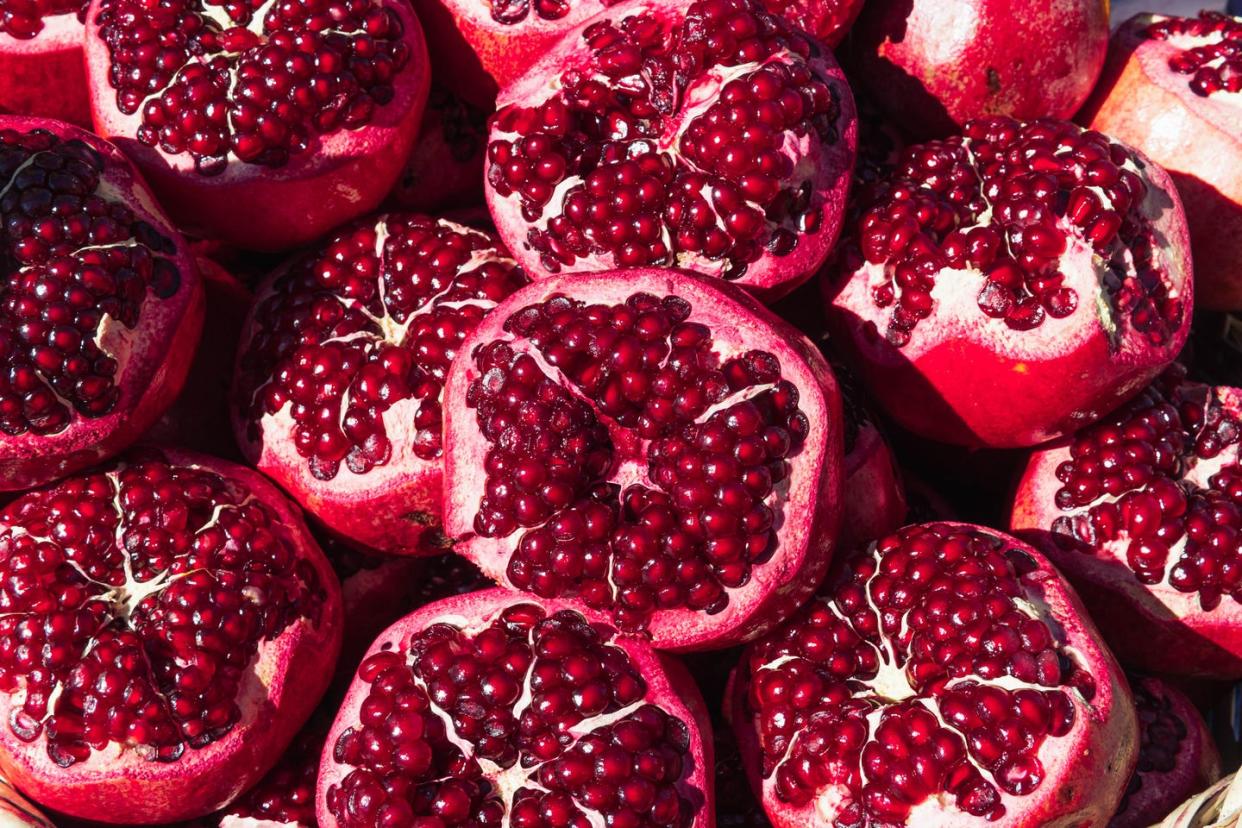 a lot of ripe red pomegranates with a cut off top, close up background