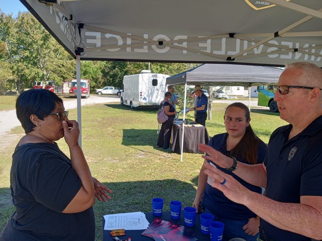Victoria Blass, center, a mental health counselor with Meridian Behavioral HealthCare, and Cpl. William "Bill" Gough of the Gainesville Police Department, talk to a woman about GPD's Co-Responder Team on Saturday during Impact Duval's Community Health Fair at Bartley Temple United Methodist Church.