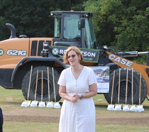 Kay Spergel standing in a yard in front of a bulldozer