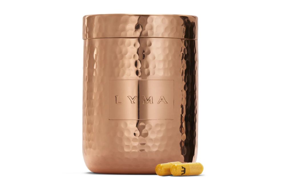A copper tin with two yellow pillows outside of it.