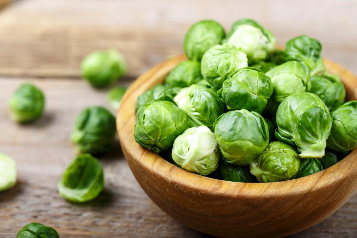 fresh organic brussels sprouts raw in a plate on wooden background