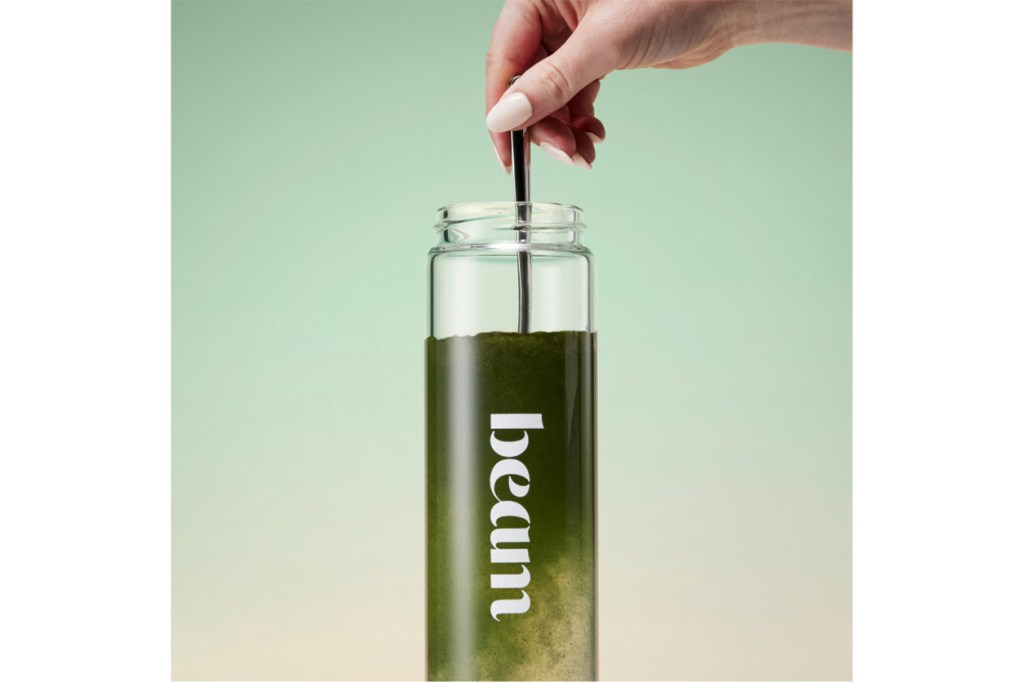 A hand holding a straw in a glass container