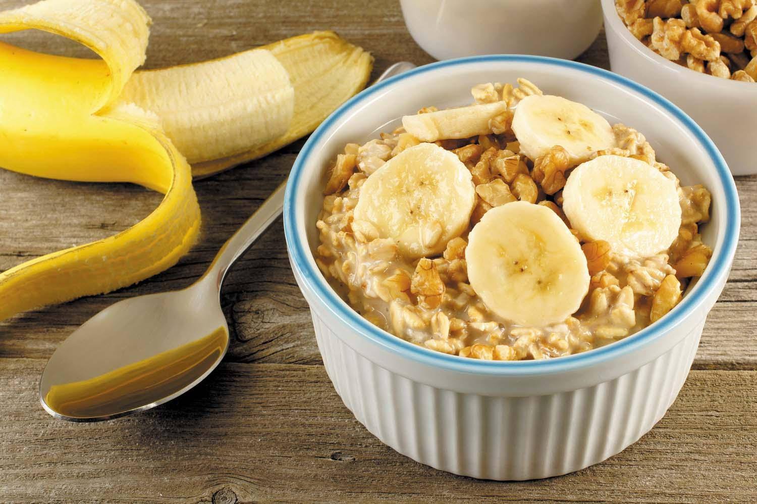 A bowl of oatmeal topped with nuts and banana slices.