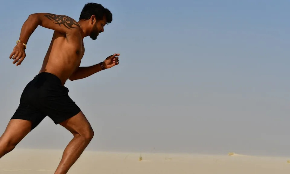 a man running on the beach without a shirt on