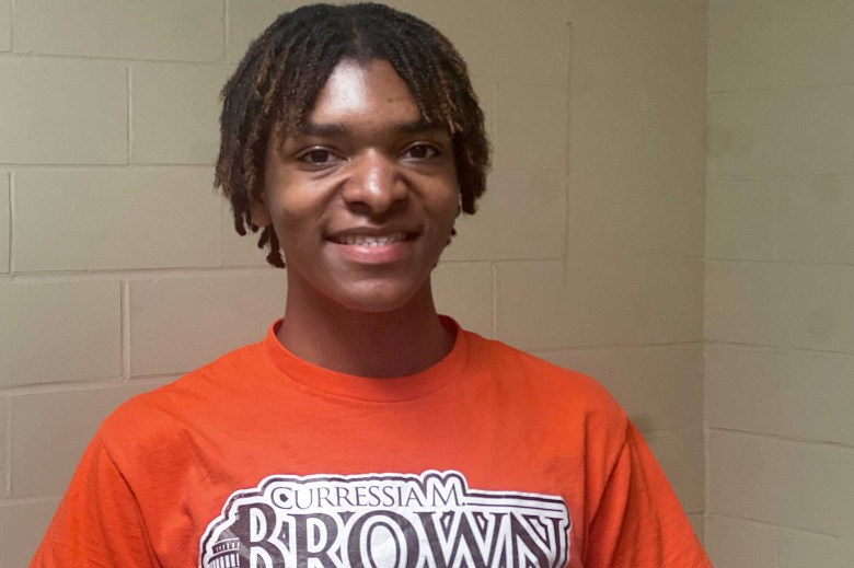 A young man in an orange shirt that reads 'Curressia M Brown'