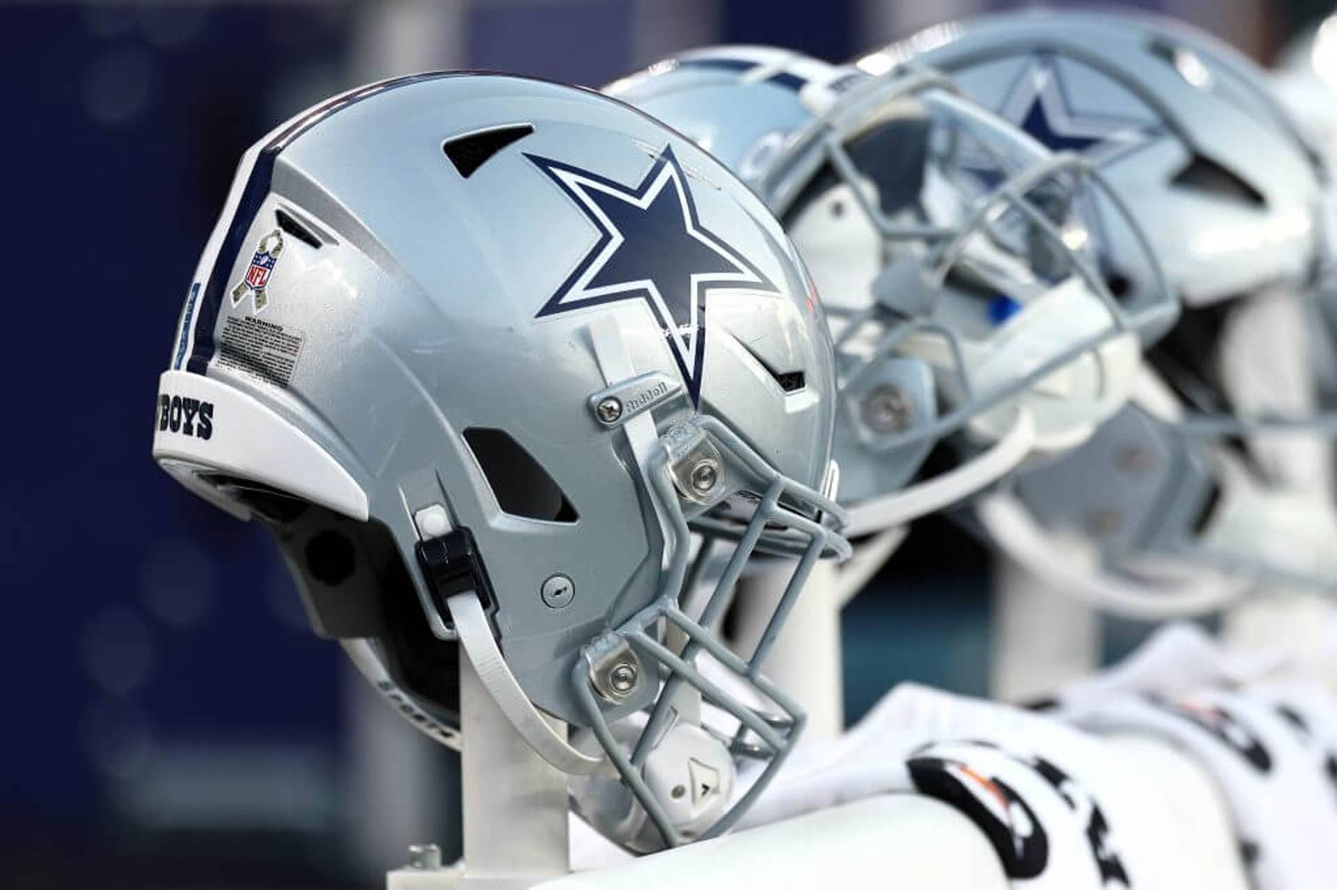 Dallas Cowboys helmets are lined up on the field during a game.