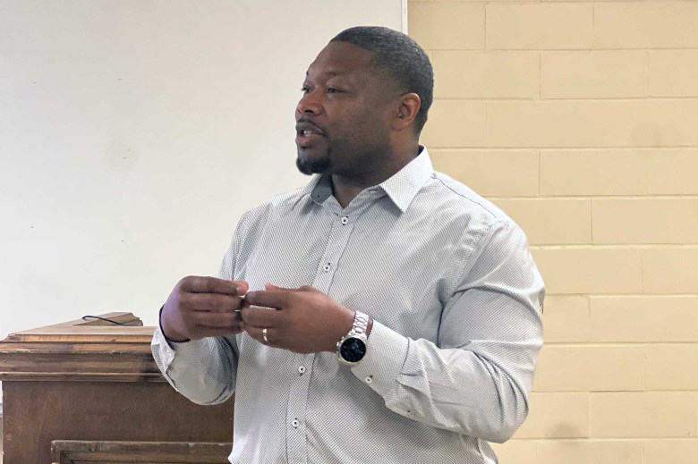 A man smiles in front of a whiteboard