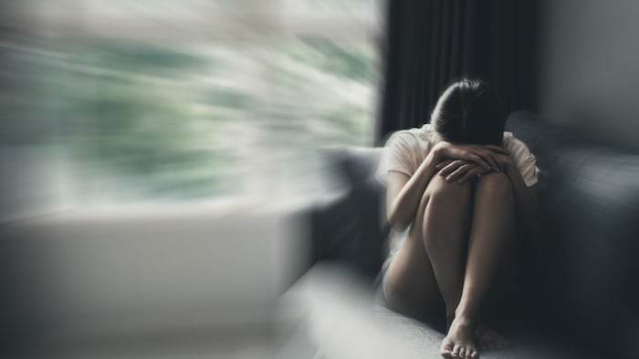 Depression and anxiety concept of woman in fetal position on the sofa with gloomy colors