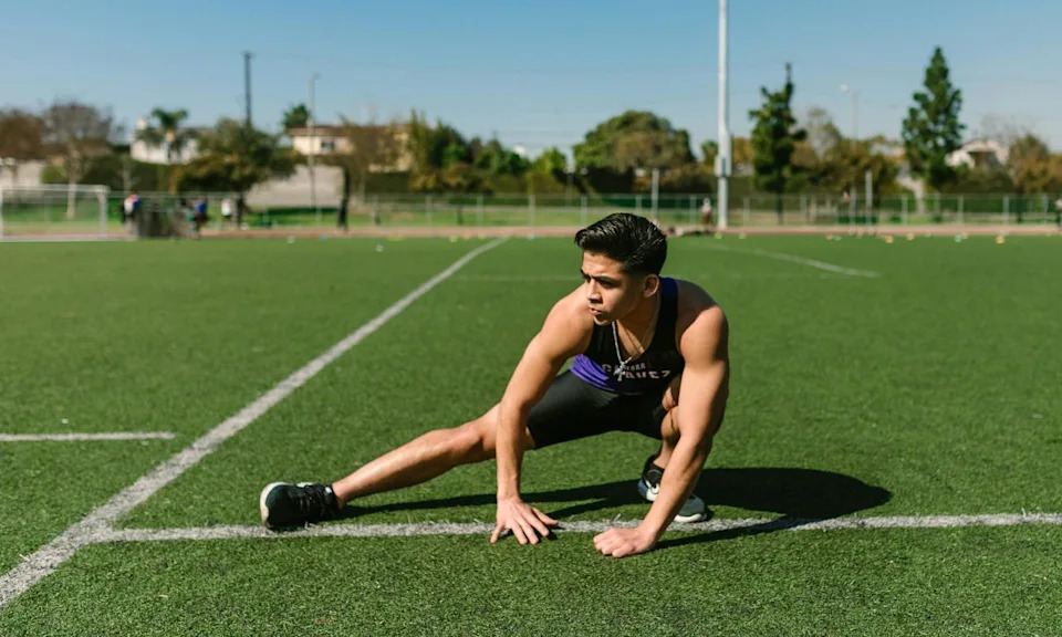 man stretching exercising outside on field