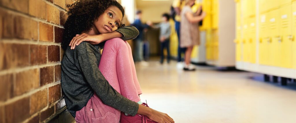 Girl in school hallway who looks sad after bullying