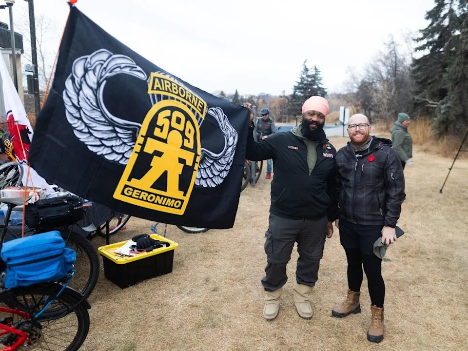  U.S. Army veteran Tegh Singh (left) holds the flag of the 509th Infantry Regiment with fellow veteran Cody Littlefield at the sixth annual Veterans Transition Network Ride for Veteran Mental Health in Calgary on Sunday, Nov. 9, 2025.
