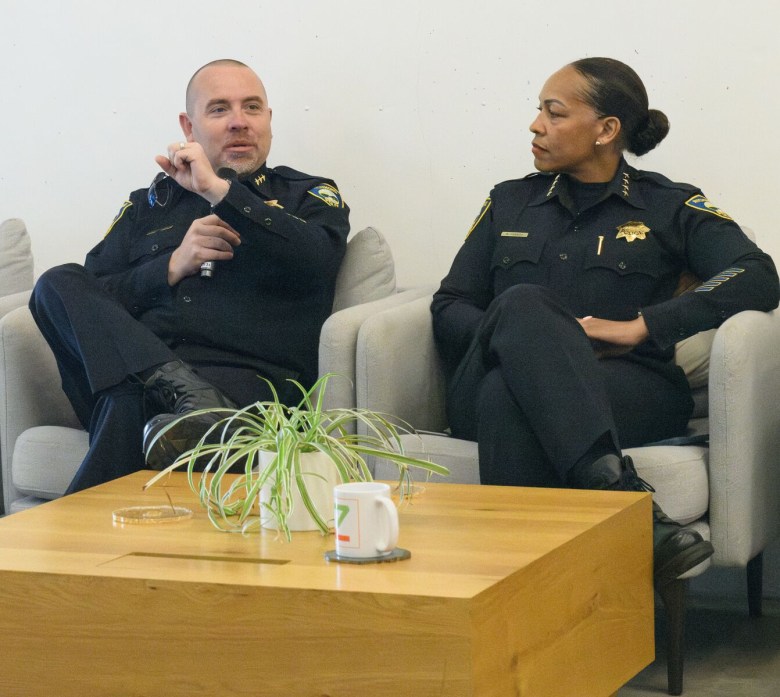 Police chief seated and a public meeting.
