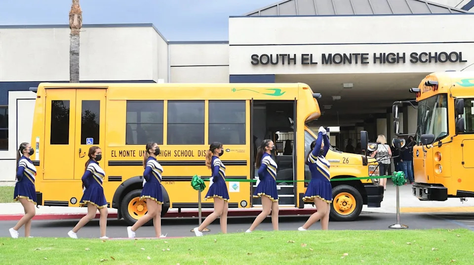 Cheerleaders from South El Monte High School walk past the school buses in August 2021 in El Monte, California. Harvard researchers say more needs to be done to determine how schools reopening during the Covid pandemic affected marginalized students (AFP via Getty Images)