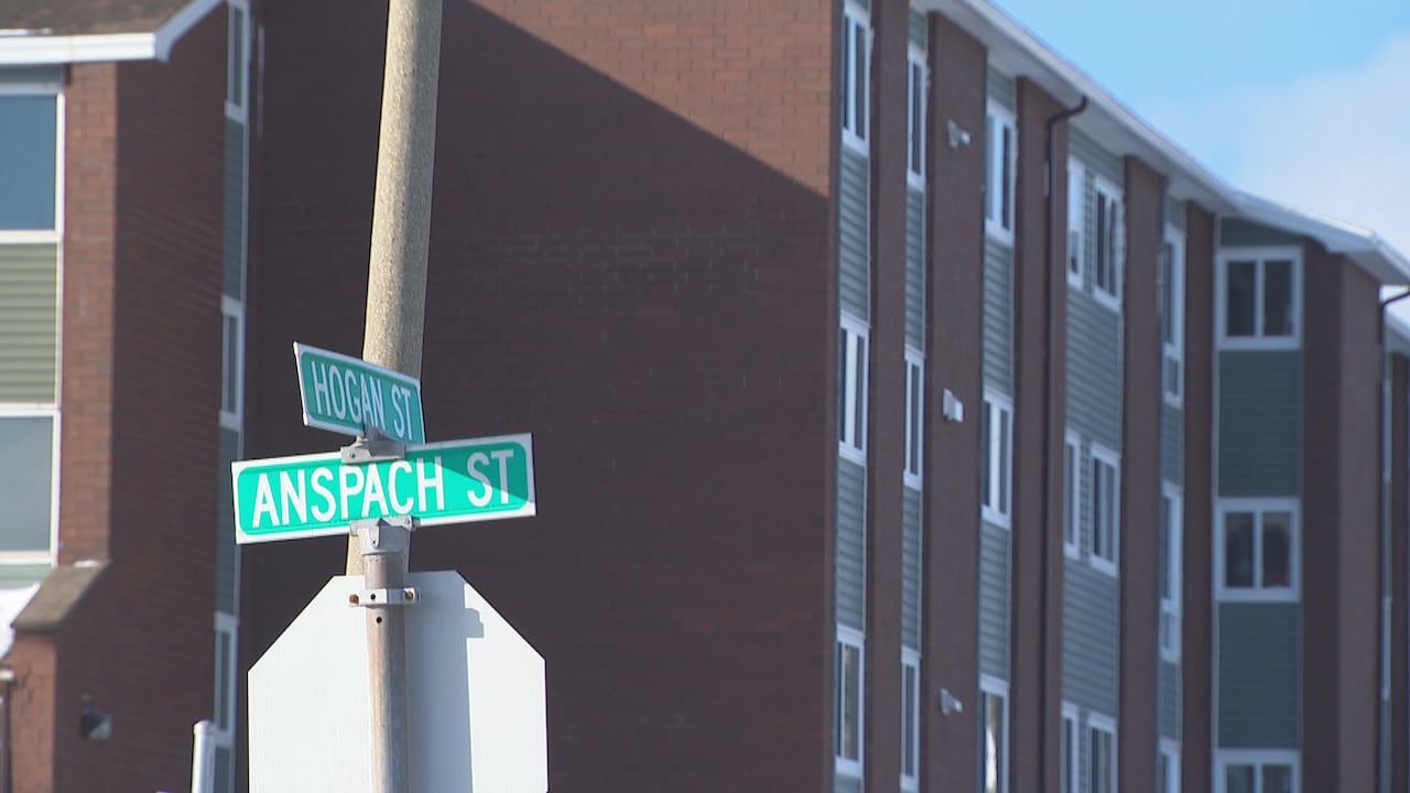 two street signs in front of an apartment building