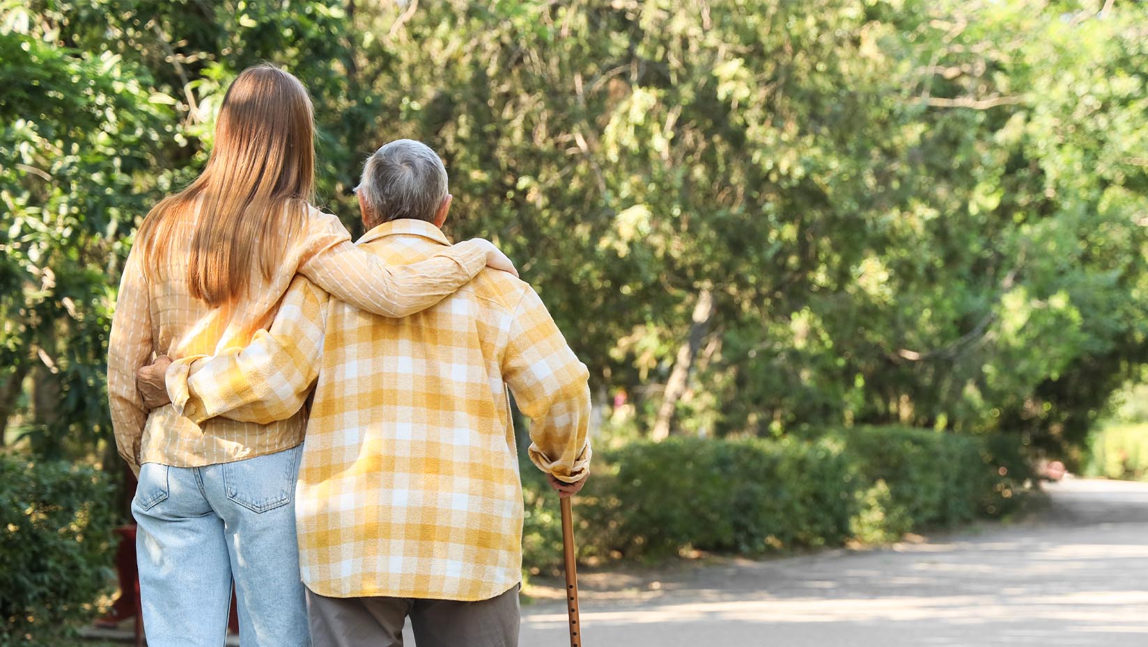 A photo of two people walking outside. One person has their arm wrapped around the other.