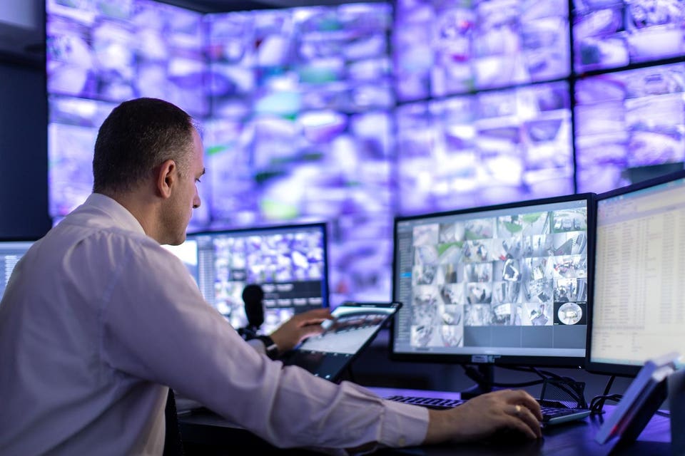 Man working in surveillance room and looking at monitors