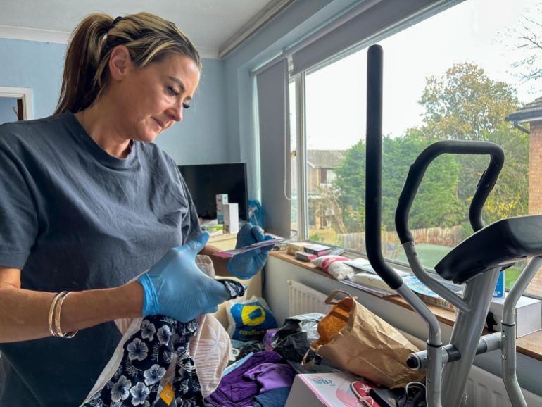 Jo Powell carefully goes through items in a hoarder's bedroom, ensuring that nothing important gets thrown away. [Amandas Ong/Al Jazeera]