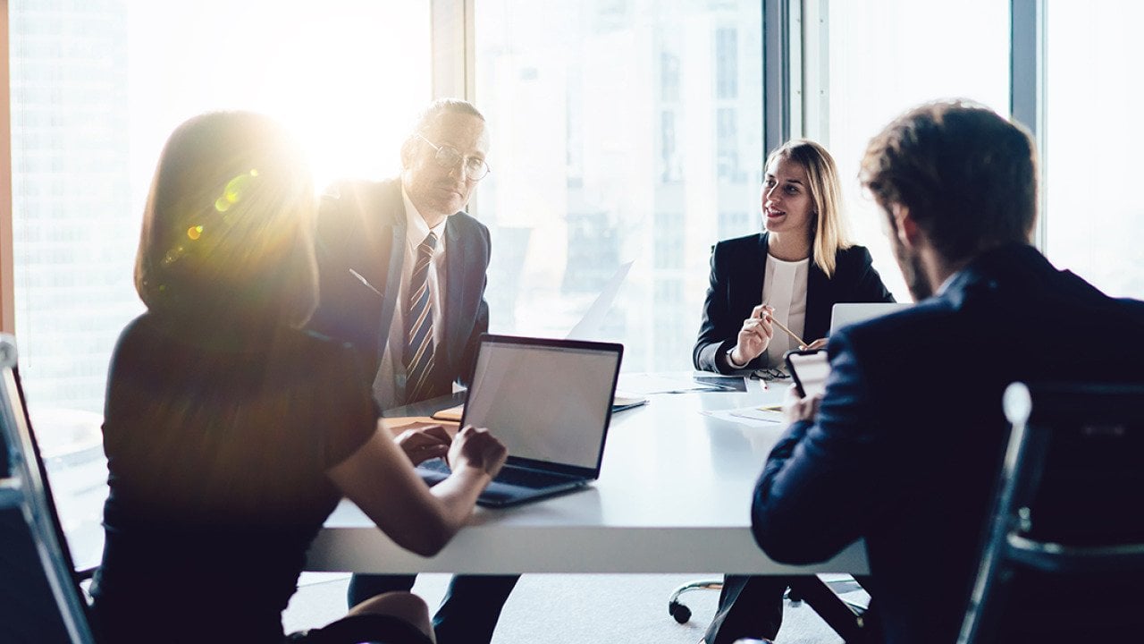 Businesspeople gathered at a roundtable in an office meeting room.