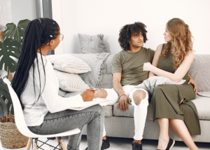 A couple attending a counseling session with a mental health professional who is taking notes, representing accessible therapy services and relationship support available through Diligence Care Plus in California and Nevada.