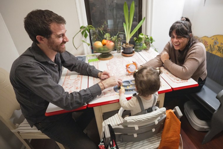 Val Calderon, right, sits with her partner Chris Russell and their child at dinner.