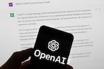 FILE - The OpenAI logo is seen on a mobile phone in front of a computer screen which displays output from ChatGPT, Tuesday, March 21, 2023, in Boston.