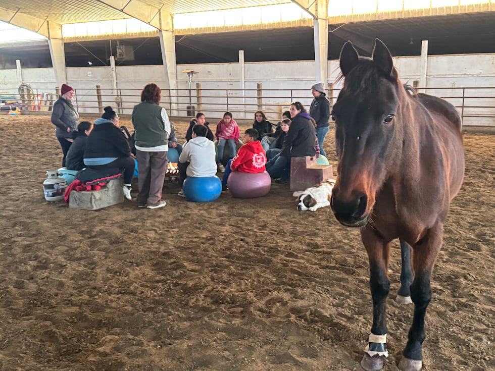 A horse stands by as children gather during a group therapy session at Red Horse Healing in...