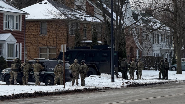 Many police officers in front of a home. 