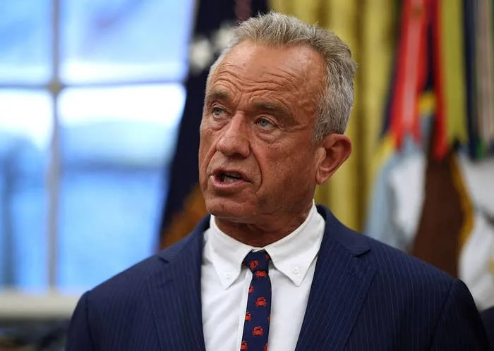 A person in a suit and tie is speaking in an indoor setting, possibly delivering news or a statement