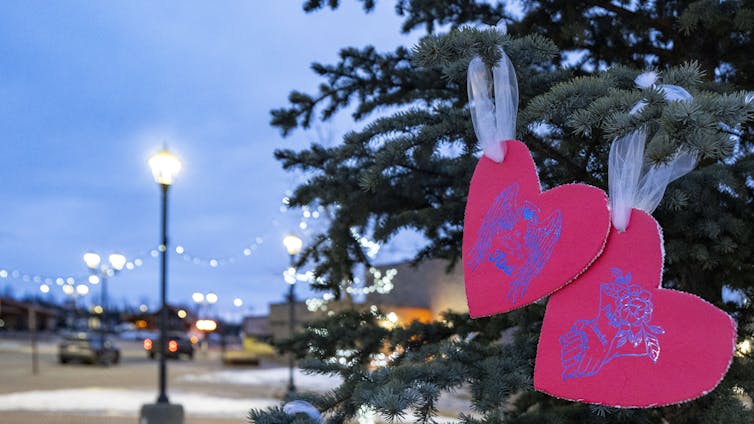 Cut-out pink hearts hang from a tree.