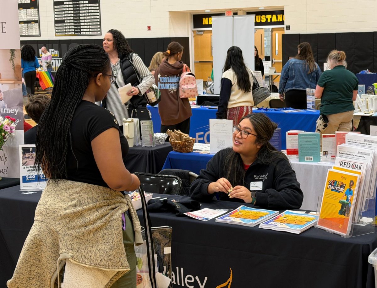 A student discusses with a representative for a mental health organization for further information.

