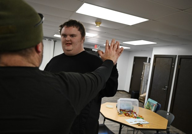 Ethan Ortengren, 18, who has autism, right, places his hand on his father Jay Ortengren's hand after his father arrives for a visit during Ethan's school day at Seven Dimensions Behavioral Health in Evergreen, Colorado, on March 16, 2026. (Photo by RJ Sangosti/The Denver Post)
