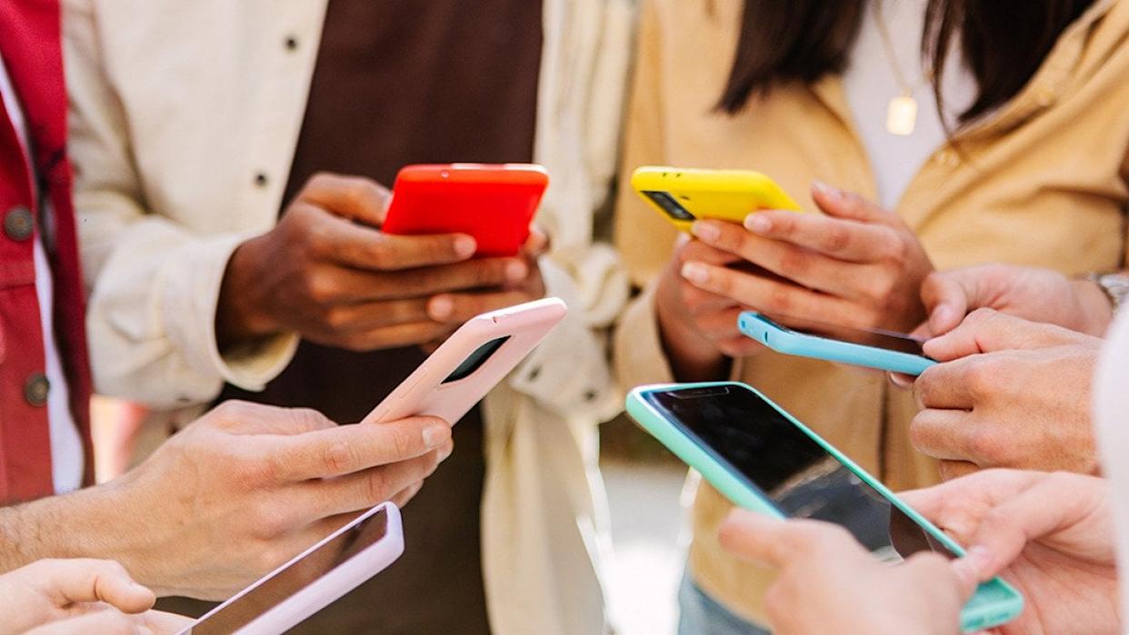 A group of young people using smartphone forming a circle outdoors. - Xavier Lorenzo // Shutterstock