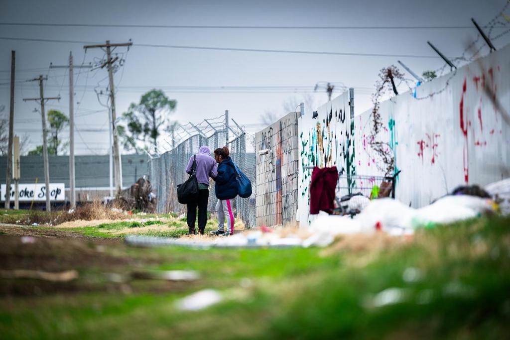 Two people stand in an alley behind a motel off East Admiral Place, March 5, 2026.