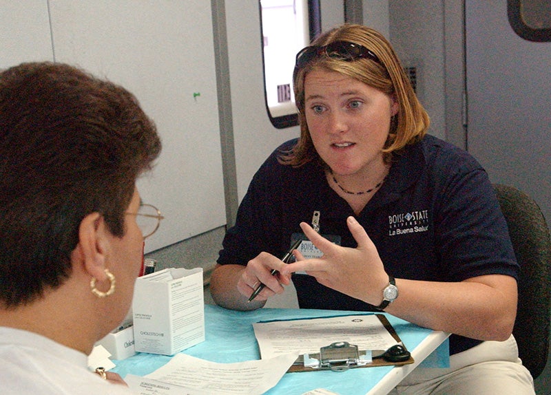 A woman conducts a health assessment with a community member.