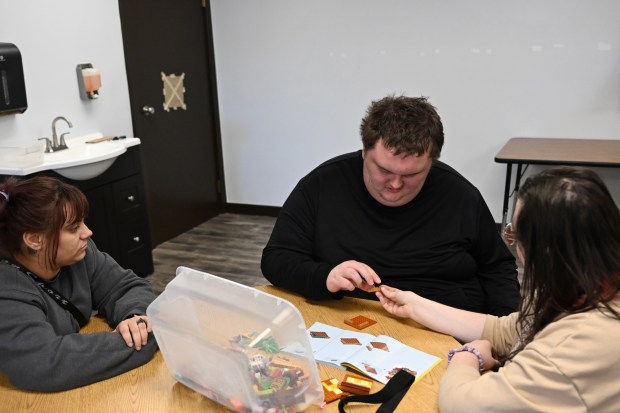 Sayeena Normanleier, a registered behavior technician (RBT), left, and Dezart Stover, a behavior technician (BT), right, help Ethan Ortengren, 18, who has autism, assemble a Lego set during therapy at Seven Dimensions Behavioral Health in Evergreen, Colorado, on March 16, 2026. (Photo by RJ Sangosti/The Denver Post)