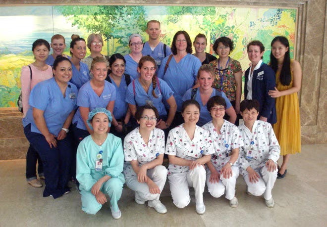 Group of 21 people posing, including Boise State faculty, students in blue scrubs, and local Chinese students and faculty.