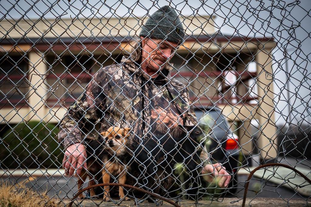 A man tries to keep his dogs from running away behind a motel on East Admiral Place in Tulsa March 5, 2026. One of the dogs belonged to his deceased wife.