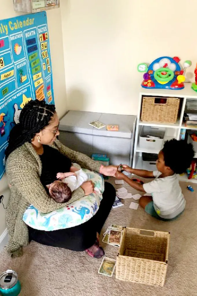 A mother holds a baby and plays with another child.