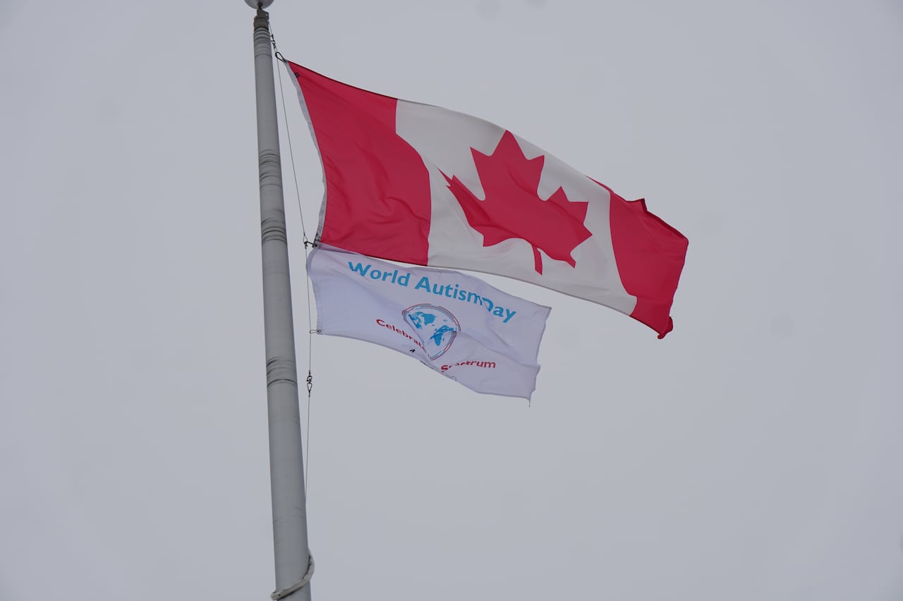 A Canada flag is seen alongside a World Autism Awareness Day flag on a pole.