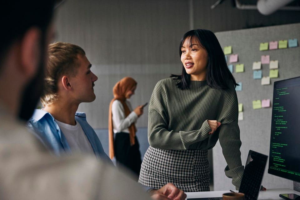 Businesswoman discussing ideas with colleagues in meeting at tech startup office