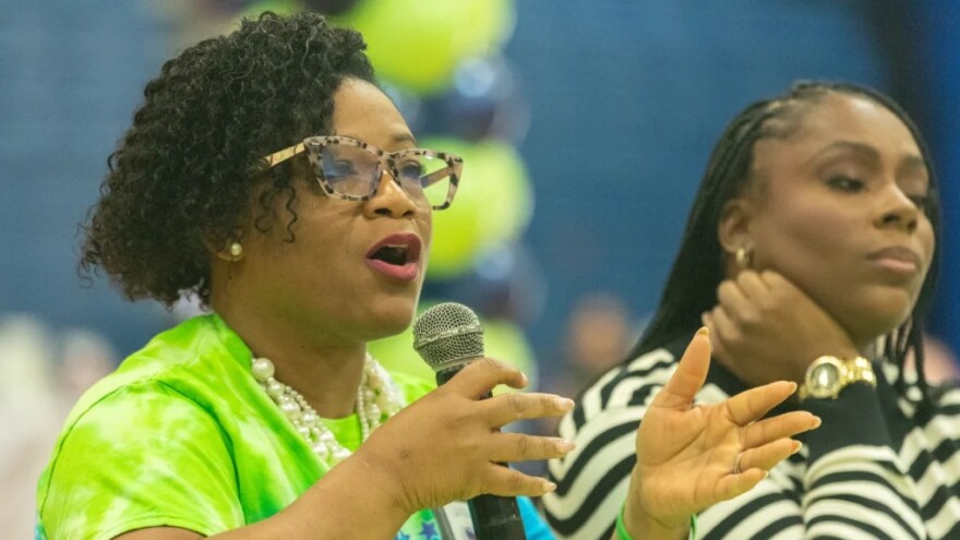 black woman in bright green top speaks into microphone  
