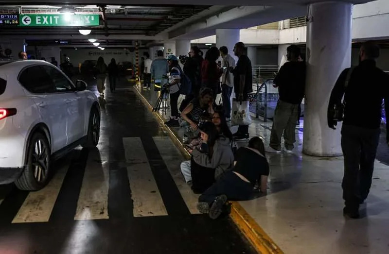 People take cover in an underground parking area as warning sirens blare in Tel Aviv on April 7, 2026. (credit: AHMAD GHARABLI / AFP via Getty Images)