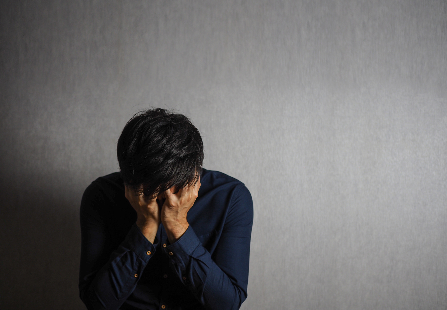 A distressed man buries his face in his hands. [GETTY IMAGES]