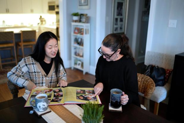 Zoie Albers and her adoptive mother, Leslie Albers, look through family photographs.