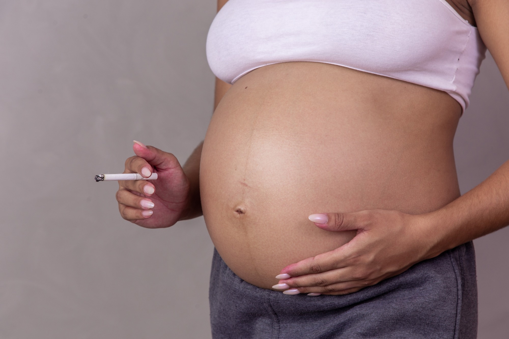 Pregnant woman with lit cigarette in hand. Concept of prohibited smoking pregnant