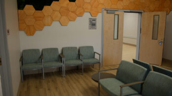 lobby with green chairs and wooden art design on wall