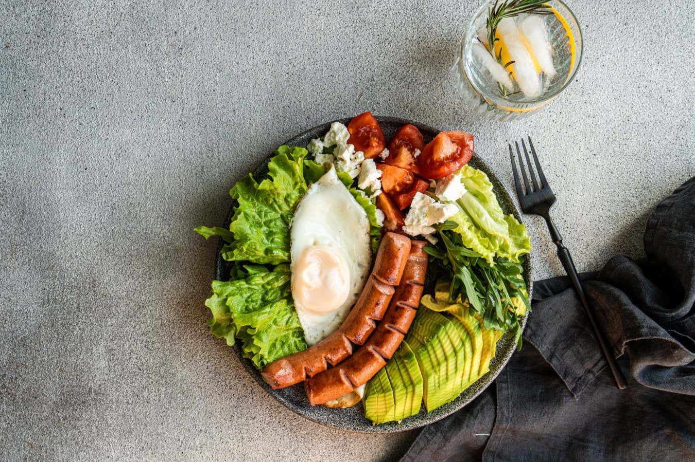 healthy ketogenic lunch plate with vegetables, fried egg and sausages