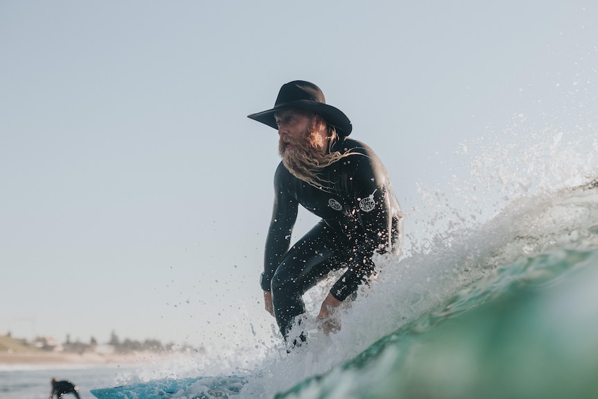 Image of Blake Johnston surfing a wave wearing a cowboy hat.