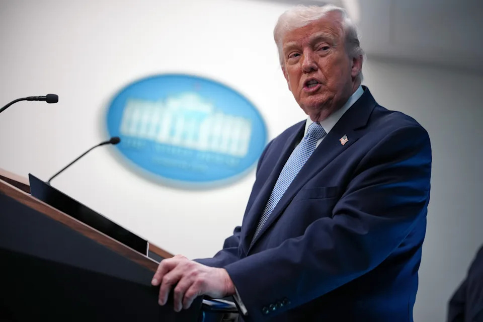Person at a podium, speaking at a press briefing. White House emblem visible in the background